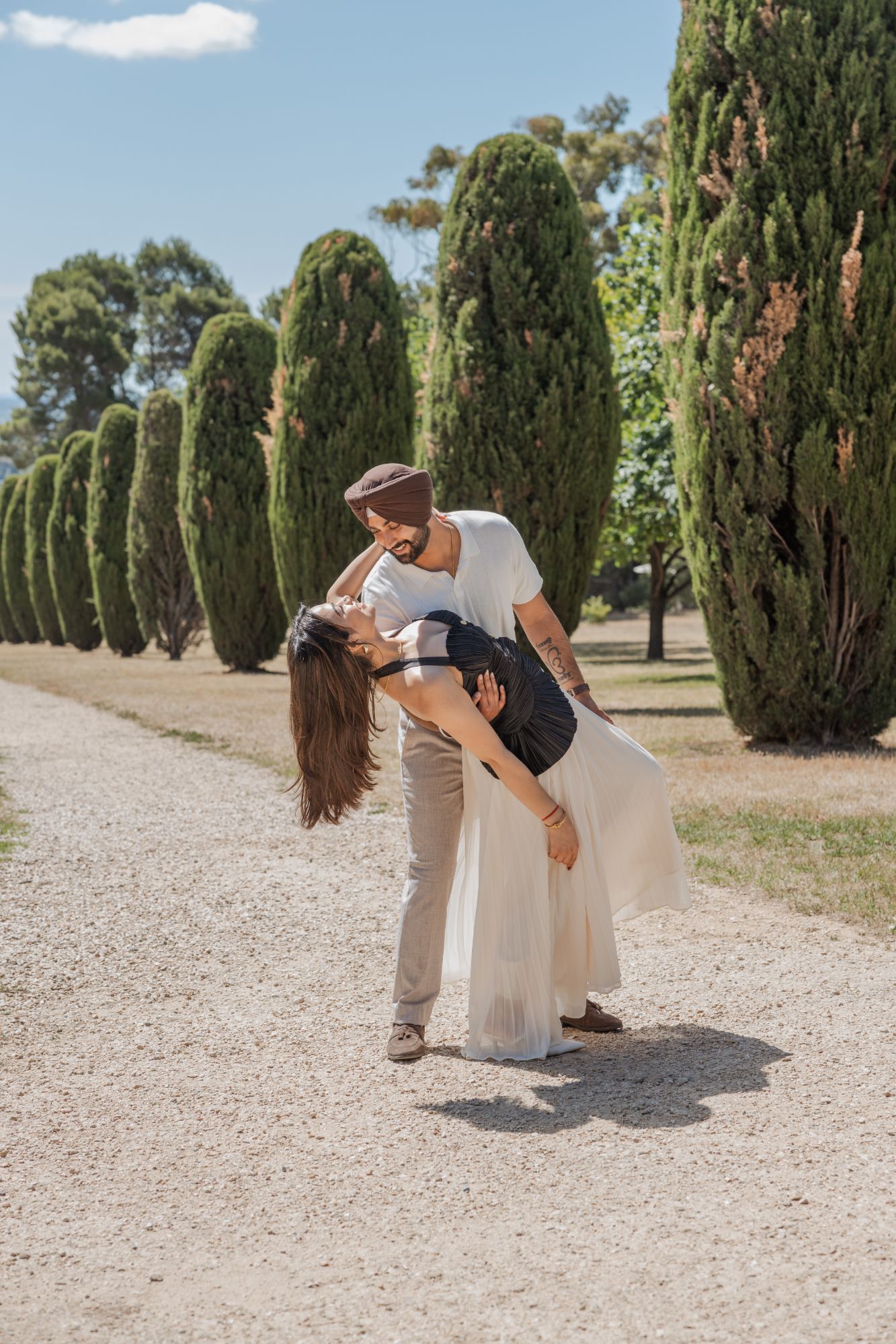 He dips her on a cypress-lined gravel path, both laughing