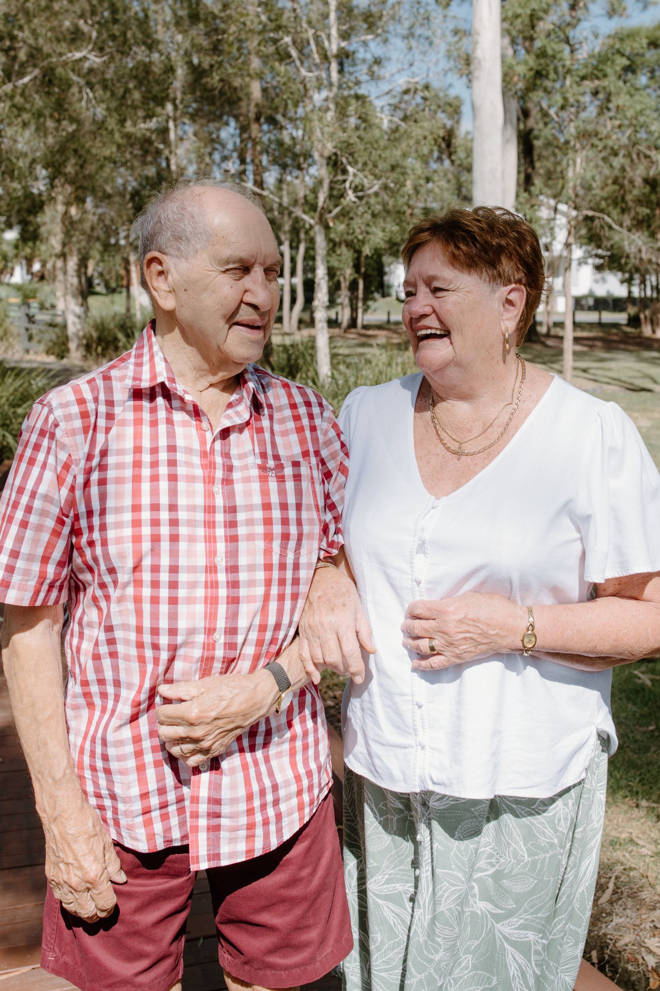 Older couple arm in arm, laughing together in a park