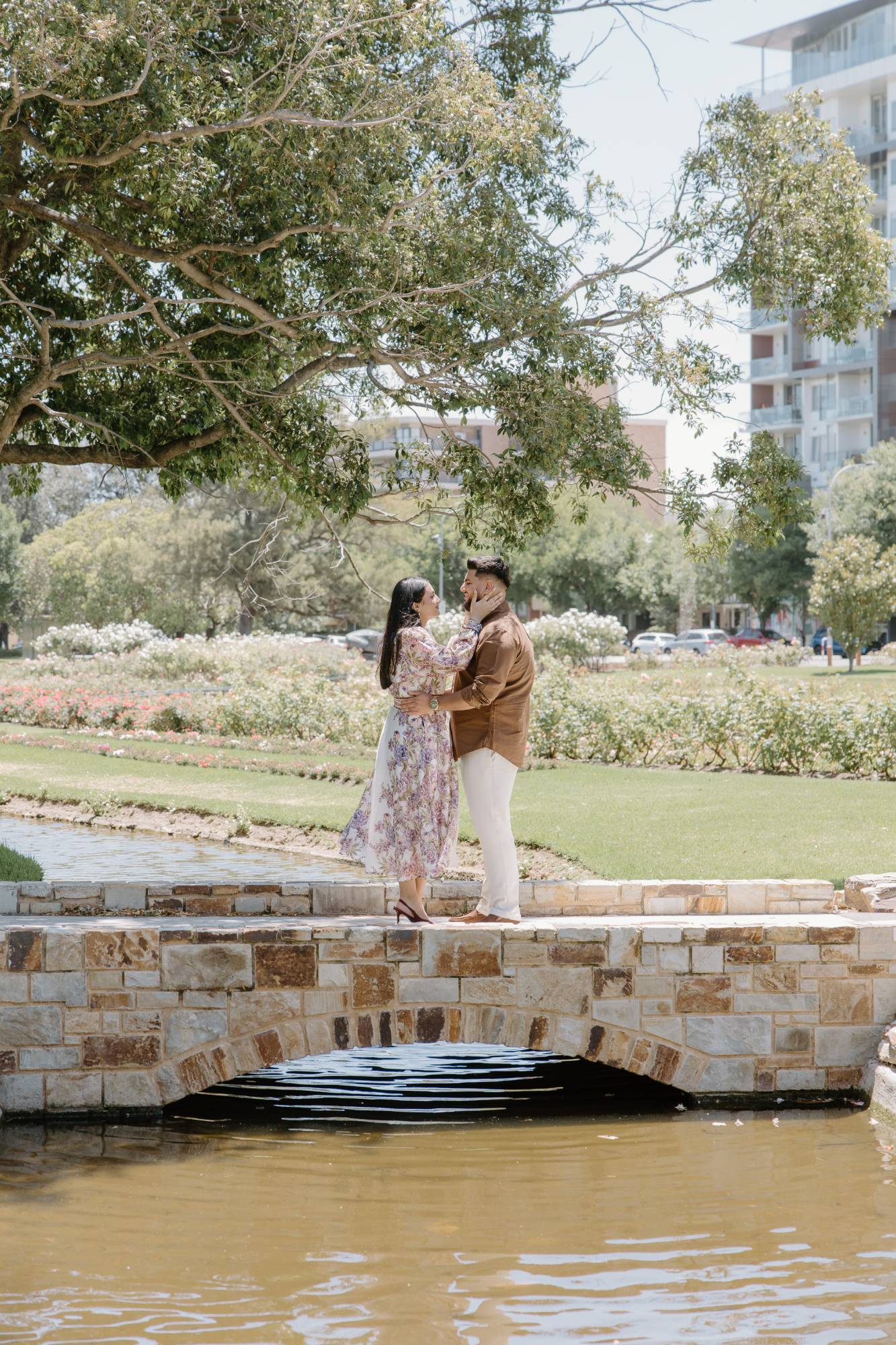 Couple face to face on a stone bridge in a rose garden