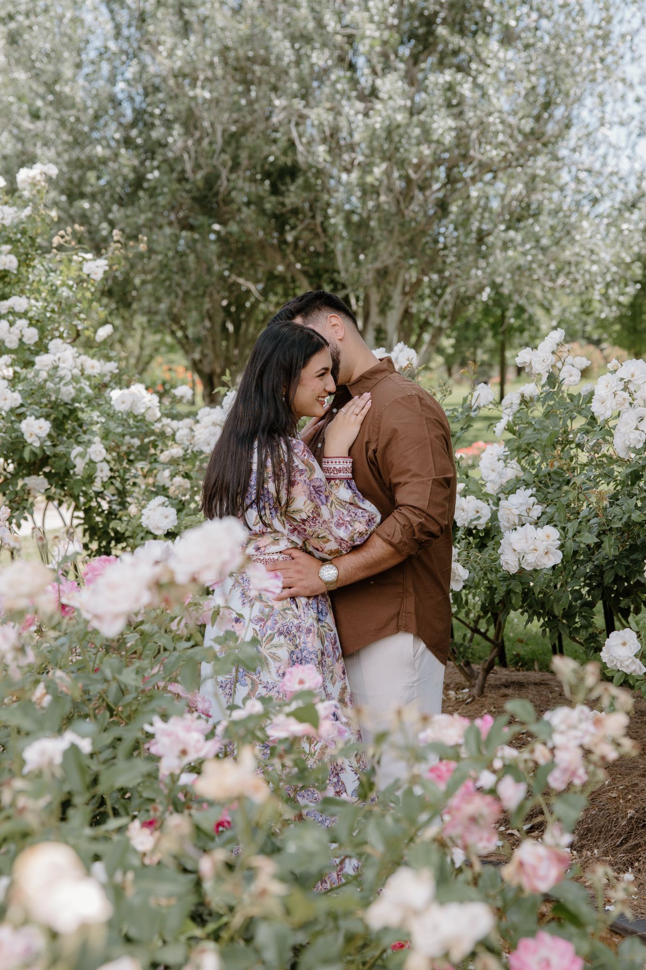 Couple embracing among white and pink roses