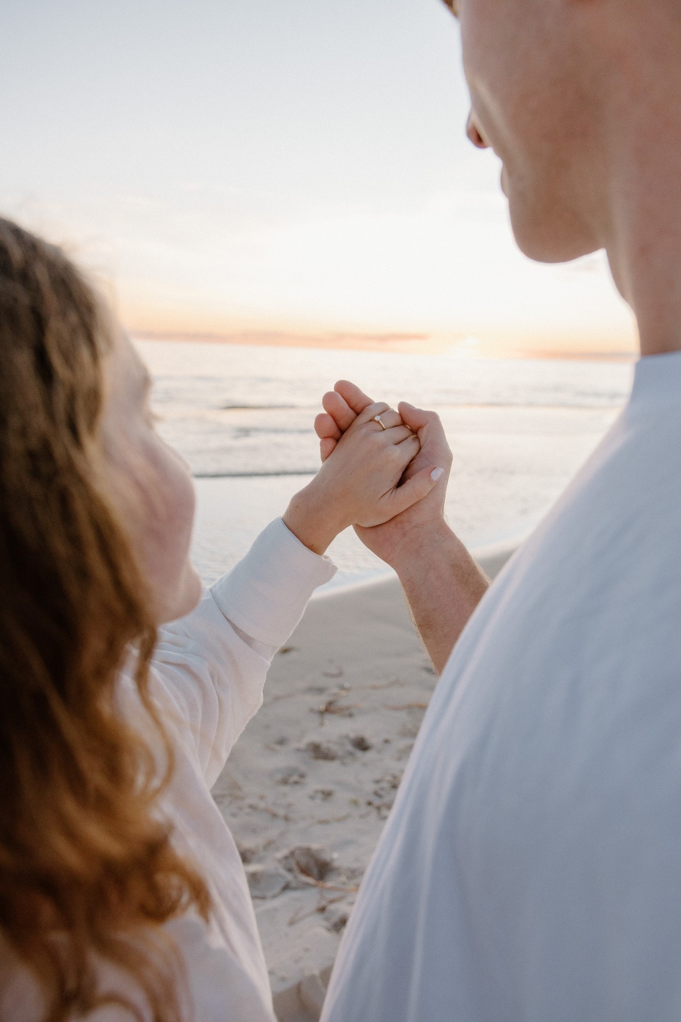 Close-up of their hands as the ring goes on, the sea behind