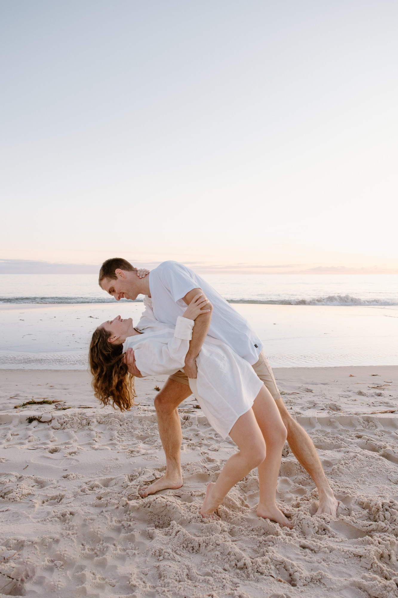 He dips her on the sand at sunset