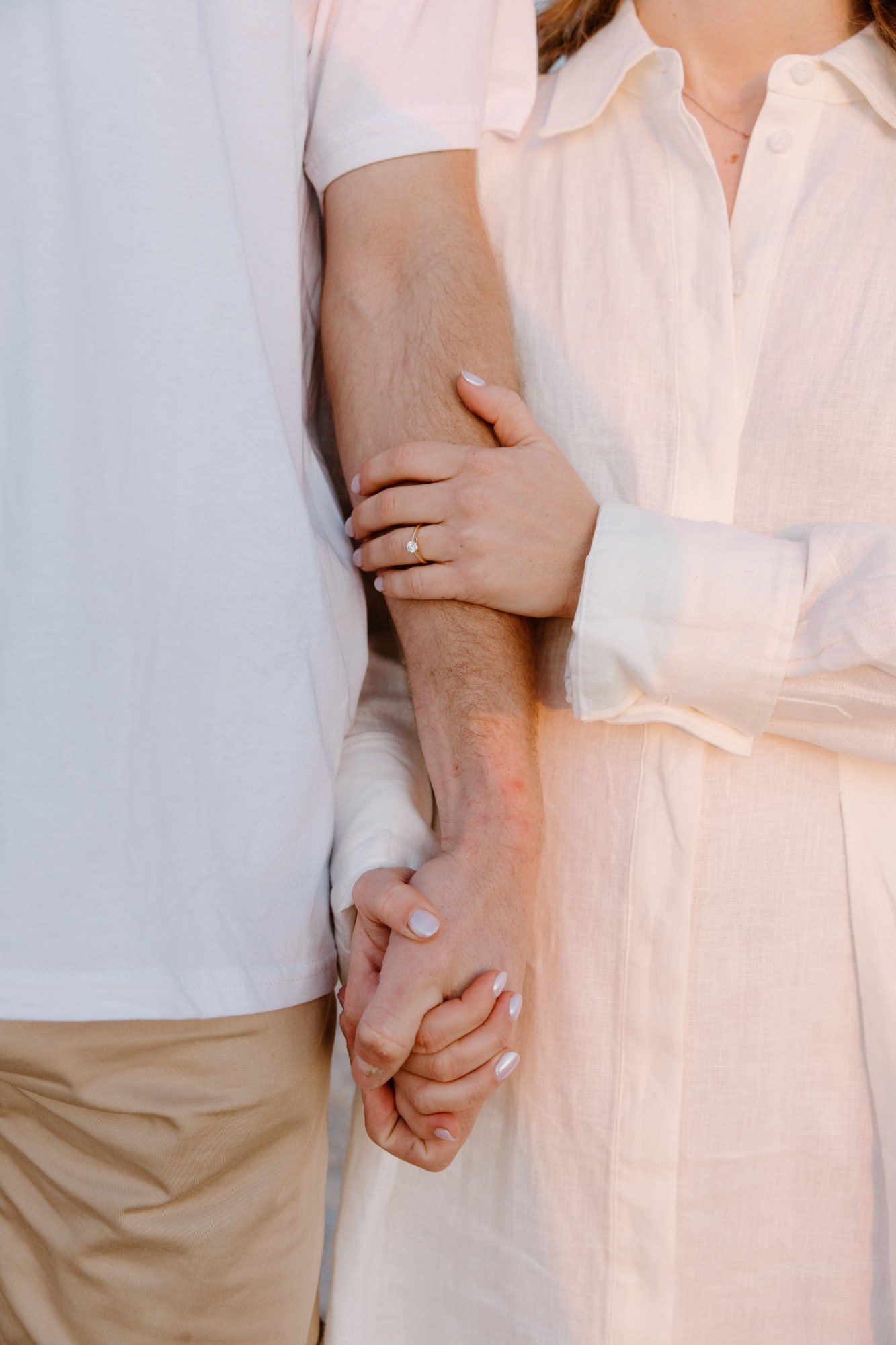 Close-up of their linked hands, her ring catching the light