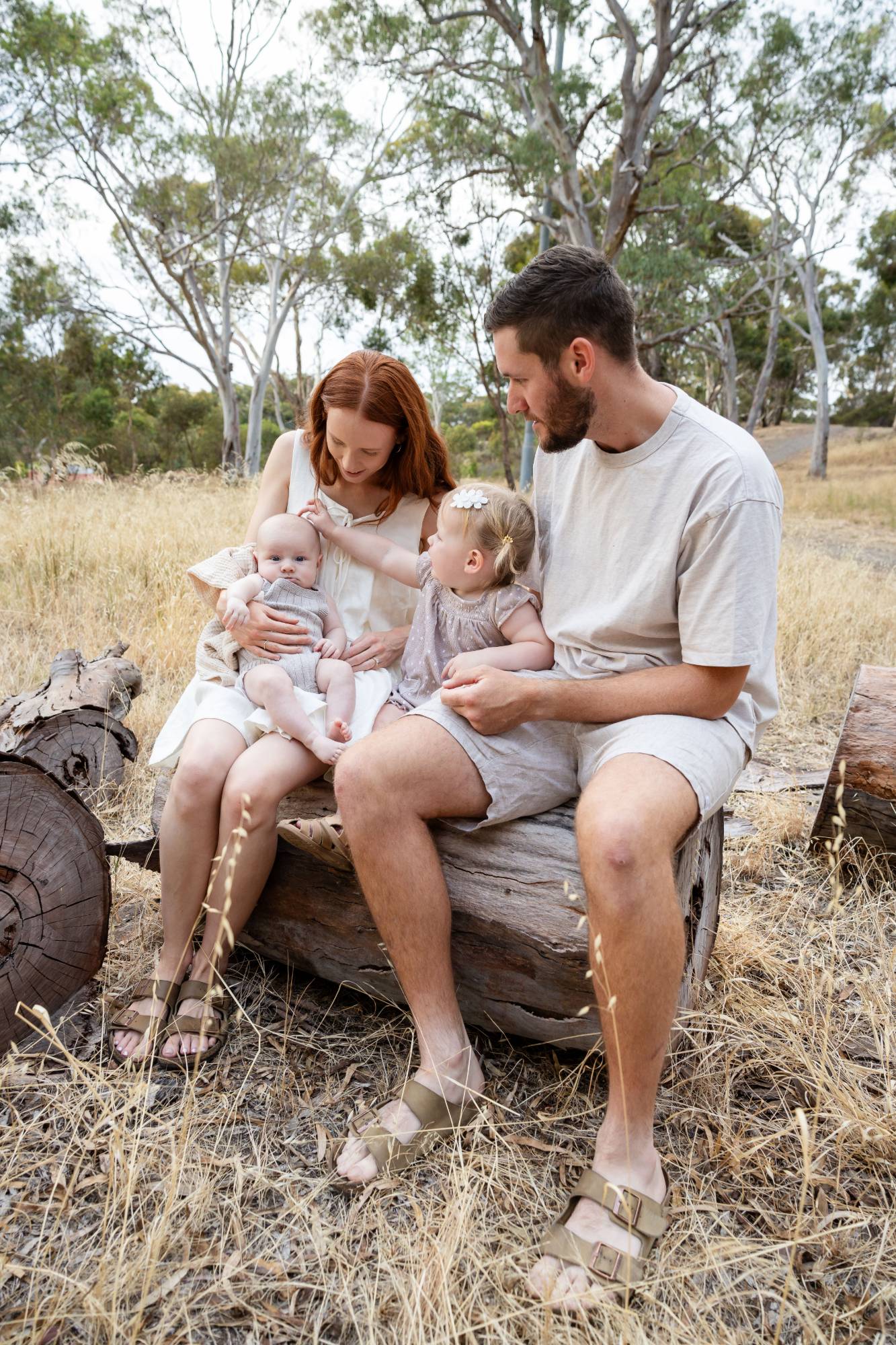 Parents with their baby and toddler on a log, laughing