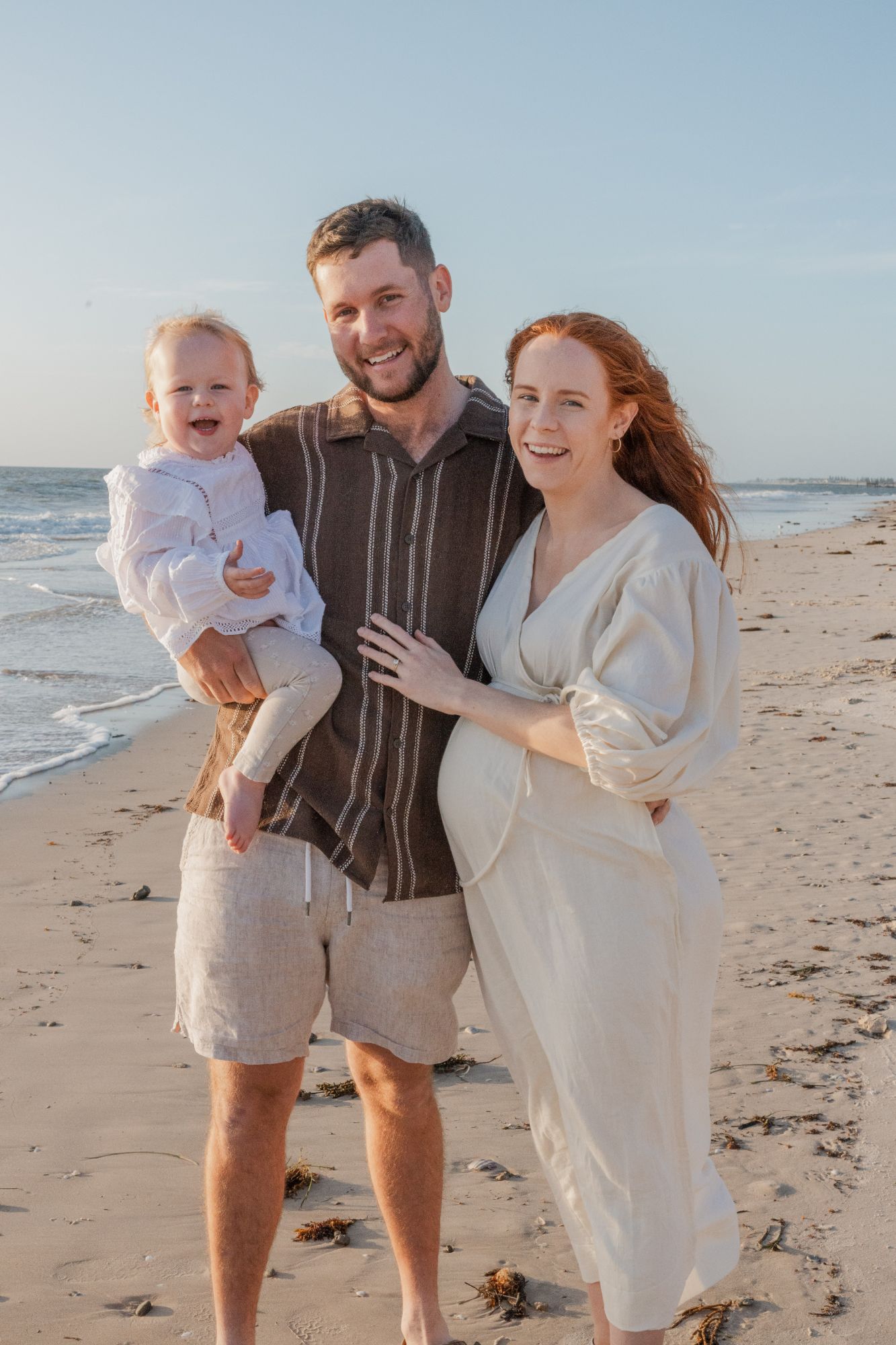 Father holding his son as the mother laughs beside them on the beach