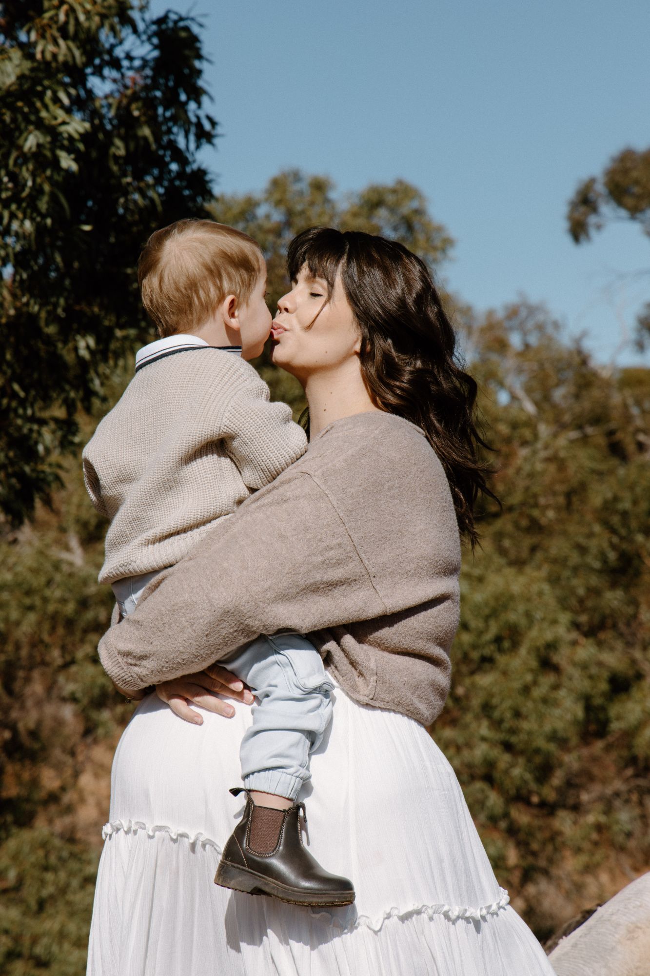Mother kissing her son’s cheek as she holds him on her hip