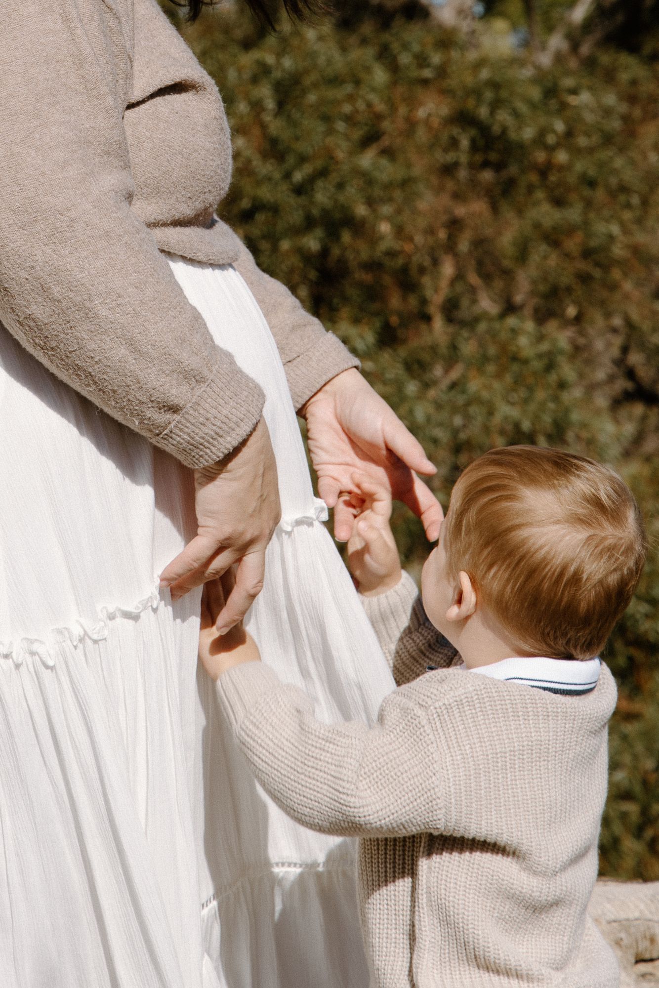 Her son reaching up to touch his mother’s bump