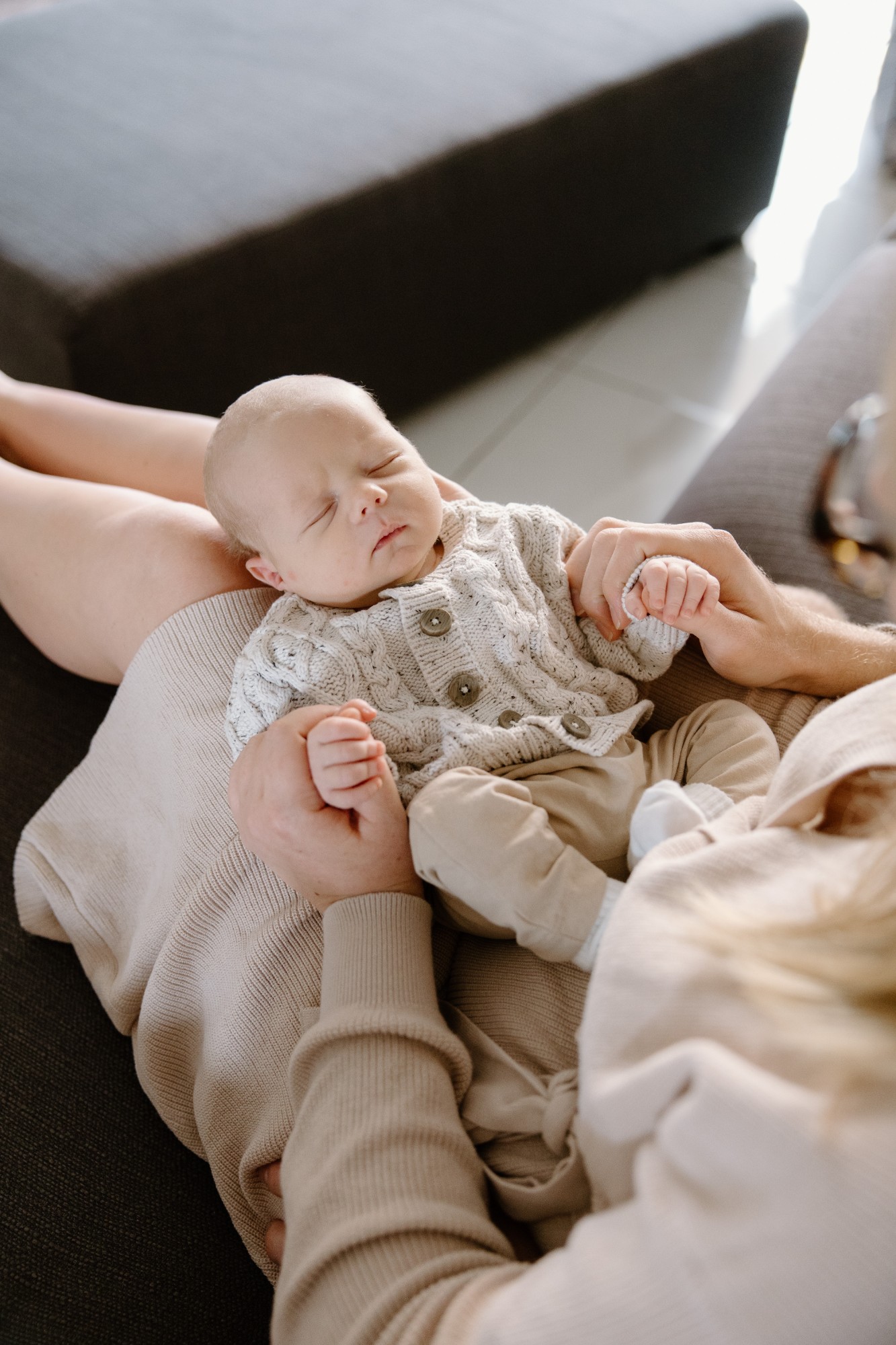 Newborn asleep in a knitted cardigan in his mother’s arms