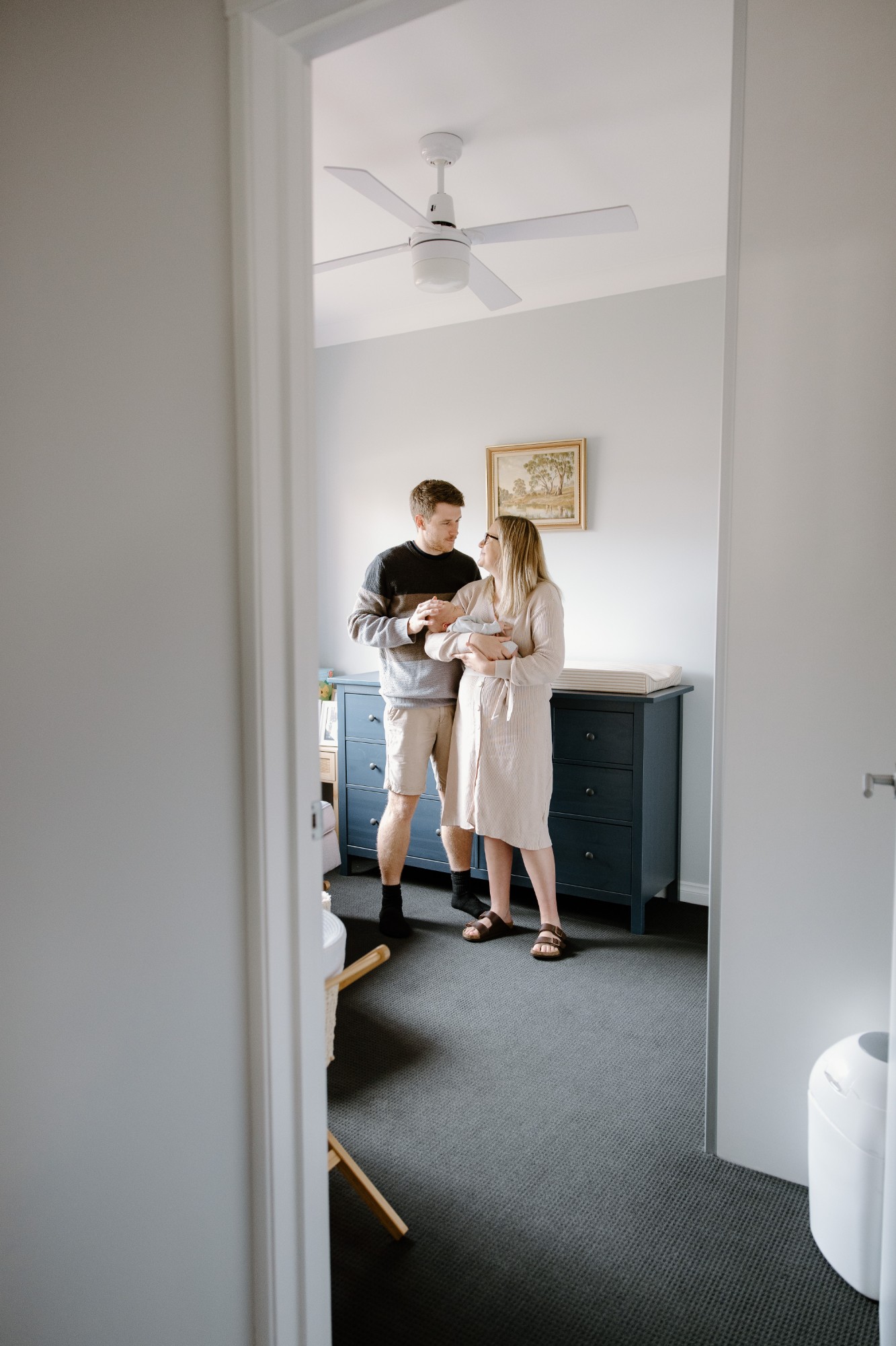 Parents with their newborn, seen through a doorway at home