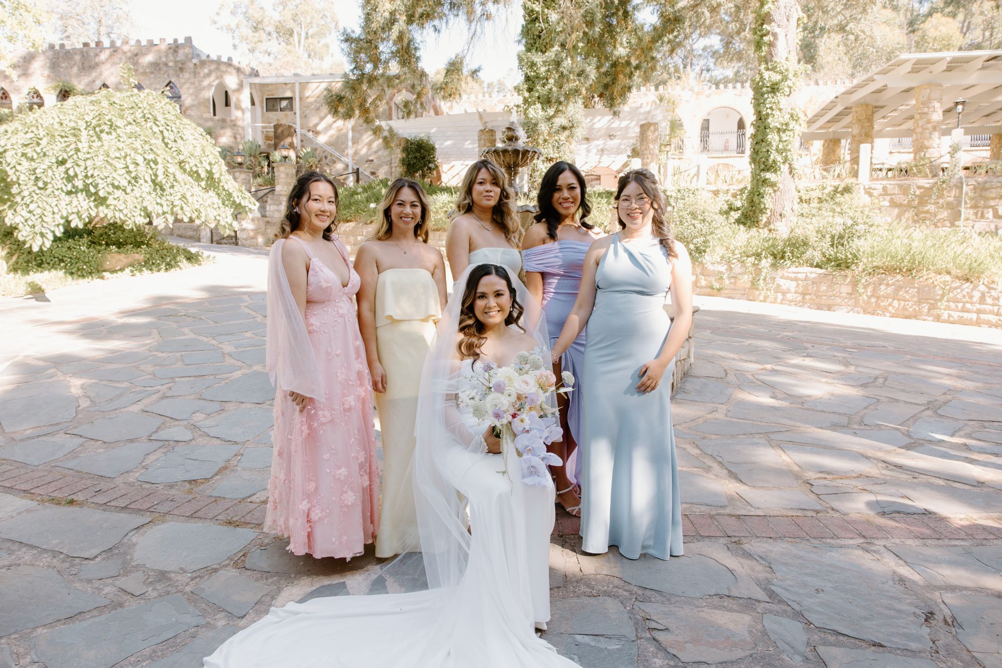 Bride seated with her bridesmaids in pastel gowns